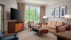 Une chambre d’hôtel moderne dotée d’une grande fenêtre, d’un téléviseur à écran plat, d’un canapé, d’une table basse et d’une table à manger.