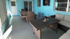 Un patio techado con mobiliario de mimbre, una mesa y un sofá.