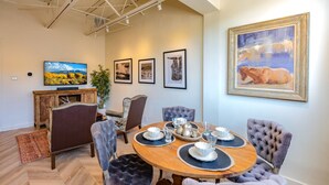 A dining area with a round wooden table, six upholstered chairs, and a large painting on the wall. - Bright & Spacious Loft at the Historic Plaza! - 375 Sq Ft (Santa Fe)