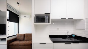 Eine moderne Küche mit Mikrowelle, Spüle und einem integrierten Kühlschrank.