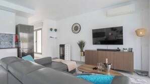 A modern living room with a grey sofa, a wooden coffee table, a flat-screen TV, and a small plant.