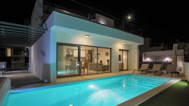 A modern house with a swimming pool, a dining area, and a kitchen.