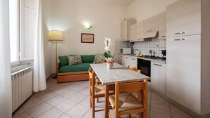 Un espacio habitable compacto con una mesa de comedor, sillas, sofá, pequeña cocina y radiador.
