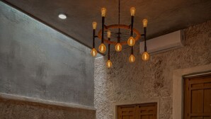 A cozy living room with a stone wall, two sofas with cushions, a patterned rug, a wooden coffee table, and a unique light fixture. - Ek Balam House - Merida Downtown (Centro)