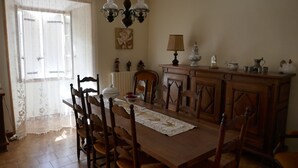 A dining room with a wooden table, chairs, a chandelier, a lace table runner, and a cabinet with decorative items. - Country house 8 persons - Dogs allowed (Valdoule)
