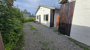 Une allée de gravier mène à une maison à l’extérieur blanc, entourée d ’une clôture en bois.