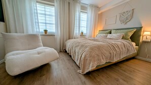 Une chambre à coucher avec un lit, une chaise et une fenêtre avec des rideaux.