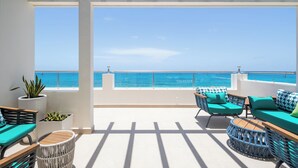 Un espacio al aire libre con mesas y sillas de mimbre, macetas con plantas y vistas al mar.