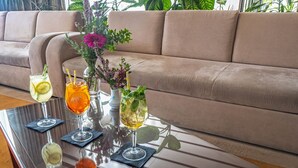 Una mesa de vidrio con bebidas y un florero en una habitación con un sofá color beige.