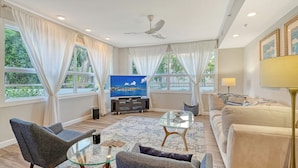 A spacious living room with a flat-screen TV, comfortable seating, and large windows with curtains. - Waterfront, Spa/Pool, Private Paradise on Longboat Key! (Longboat Key)