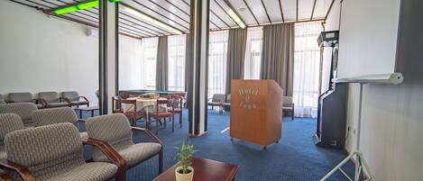 Une chambre d’hôtel avec un tapis bleu, des meubles en bois, un pupitre en bois et un écran de projection.