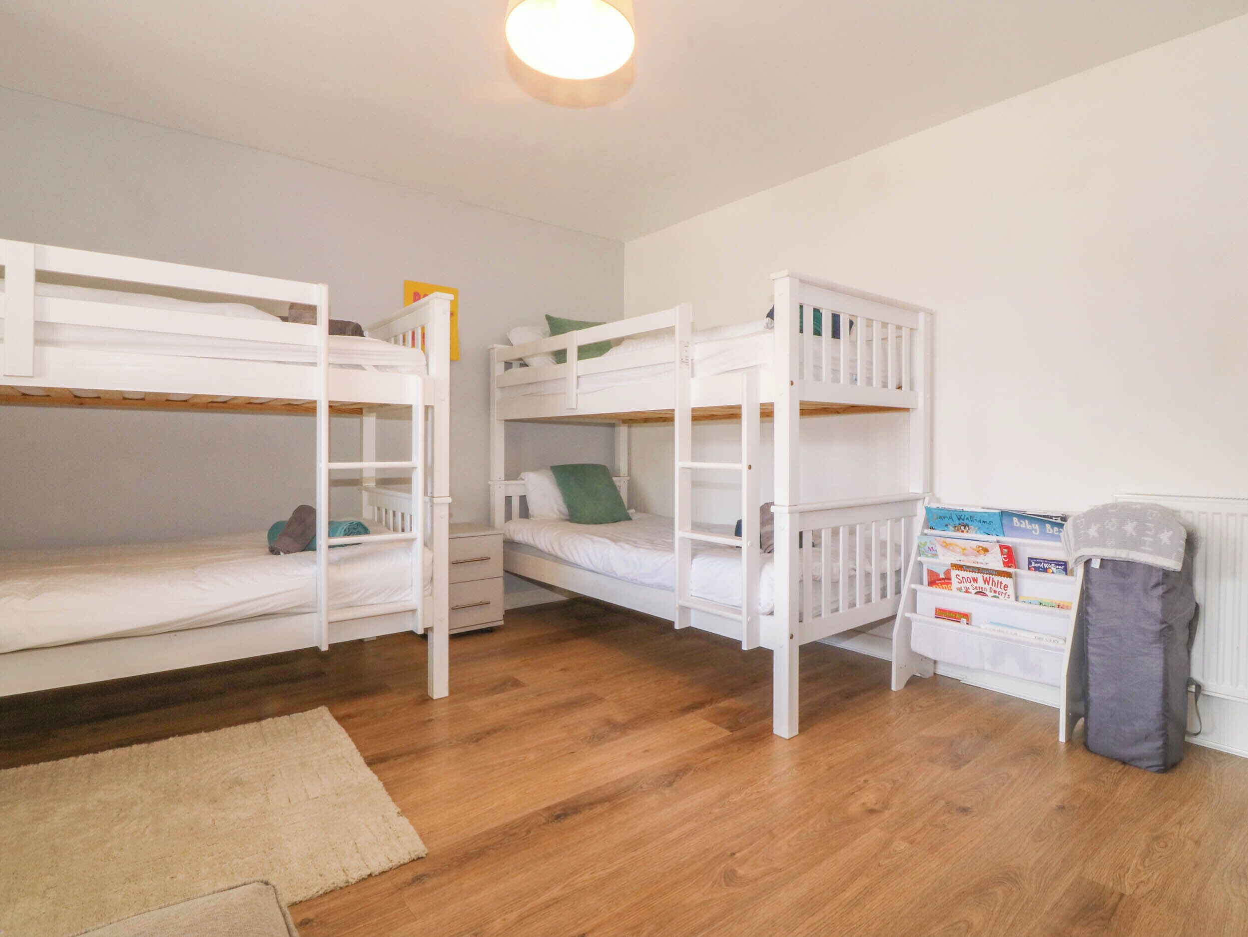 A room with three bunk beds, a small desk, and a radiator.