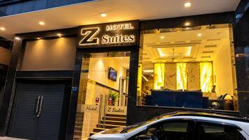 A hotel entrance with a sign for 'Z Suites' and a visible reception area with a seating arrangement.