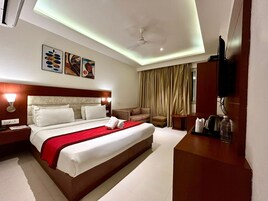 Una habitación de hotel moderna con una cama grande, un escritorio, un televisor y un ventilador de techo.