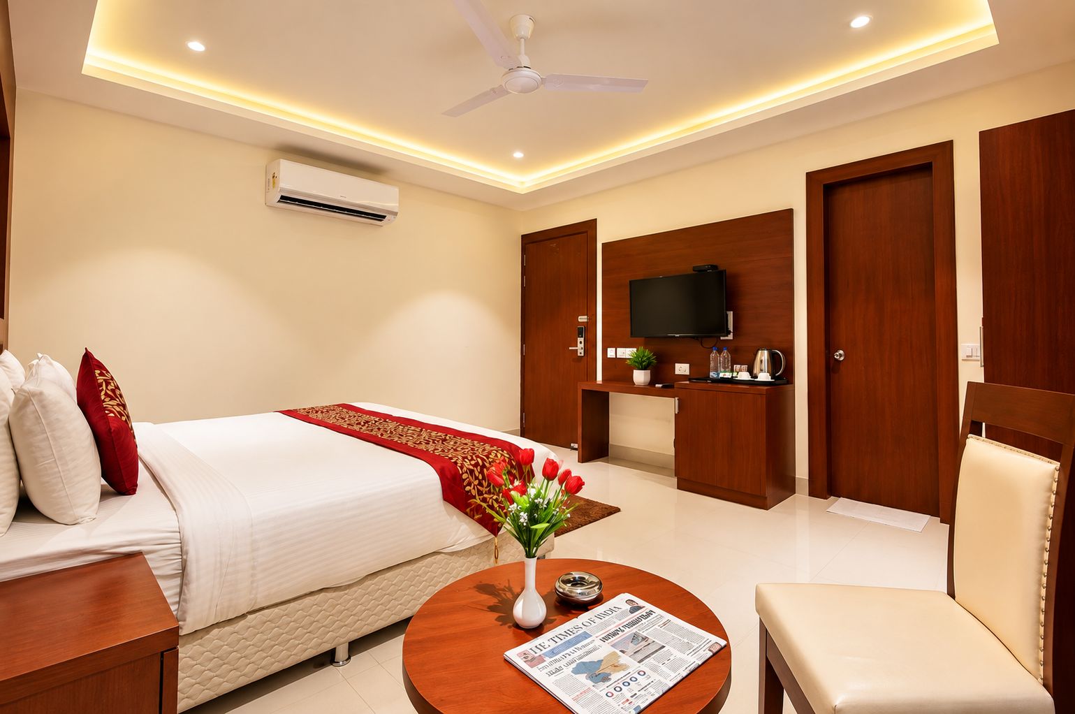 A hotel room with a bed, a desk, a television, and a seating area.