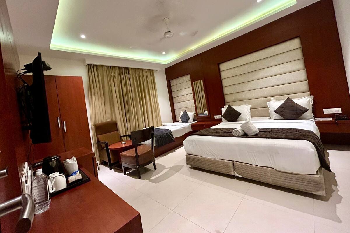 A hotel room with a large bed, a desk with a chair, a vanity, and a bathroom.