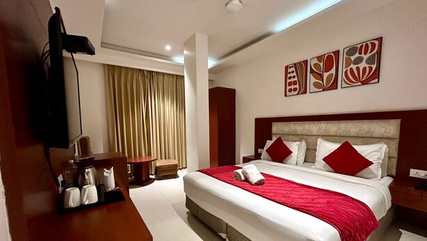 A hotel room with a large bed, a TV, a coffee station, and a view of the outdoors. - Z Suites Hotel Mahipalpur IGI Airport (New Delhi)
