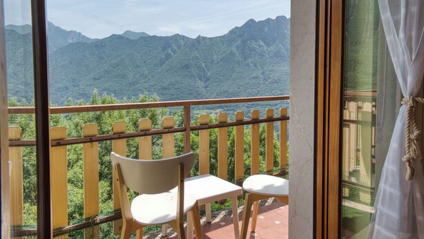 A balcony with wooden chairs and a view of green mountains. - Grigna Mountain View (Narro-indovero)