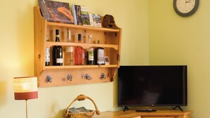 A wooden shelf with various bottles and a television on a wooden stand. - Grigna Mountain View (Narro-indovero)