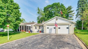 Un garage attenant à une maison, orné d’un drapeau américain, doté d’un porche abrité et d’une pelouse bien entretenue.