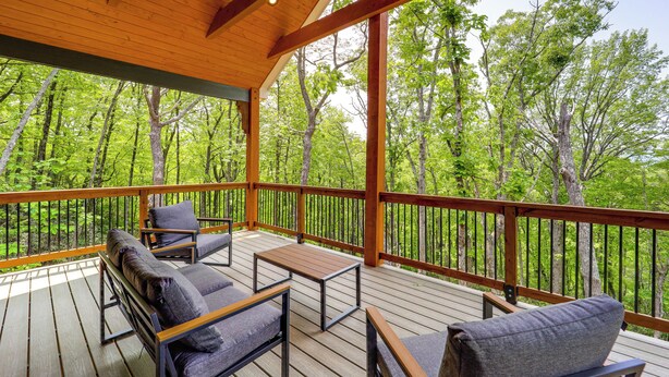 Una terraza cubierta al aire libre con muebles de madera y vista a un bosque.