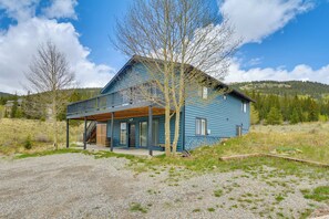 A blue house with a covered porch, a gravel driveway, and a forested hillside in the background. - Hike, Fish, Ski & Explore: Cabin Near Breckenridge (Alma)