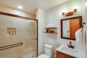 A modern bathroom with a glass shower enclosure, a white toilet, a wooden vanity with a sink, and a mirror with a wooden frame. - Hike, Fish, Ski & Explore: Cabin Near Breckenridge (Alma)