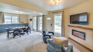 A spacious room with a large dining table, comfortable seating, a fireplace, and a TV mounted on the wall.