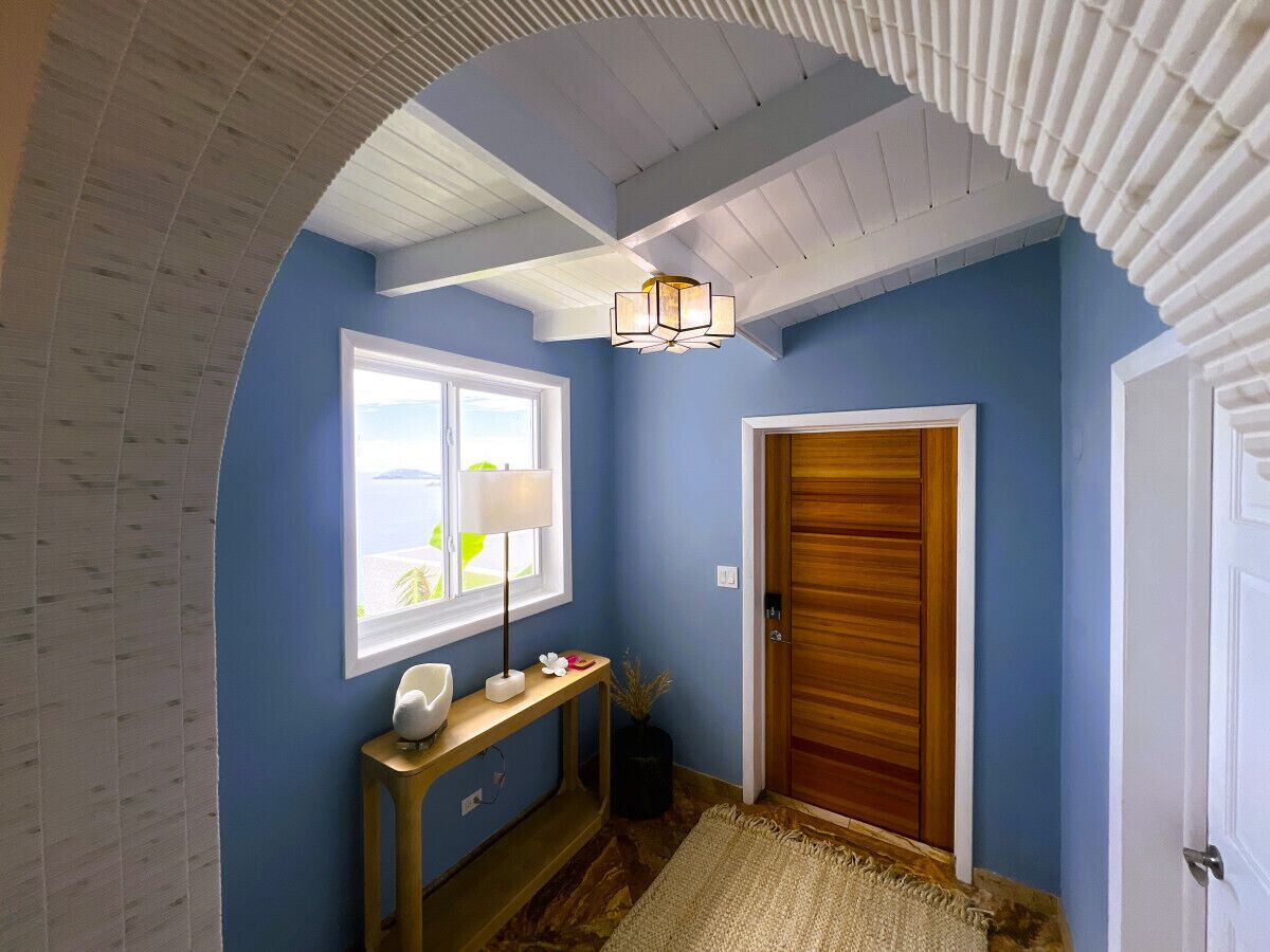 Un couloir avec une porte en bois, une fenêtre à cadre blanc, une lampe et une console.