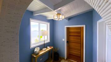 A hallway with a wooden door, a white-framed window, a lamp, and a console table.