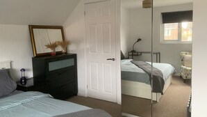 Un dormitorio con dos camas, un aparador, un espejo y una ventana.
