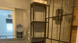 Un baño moderno con cabina de ducha de vidrio, un lavamanos blanco y un espejo.
