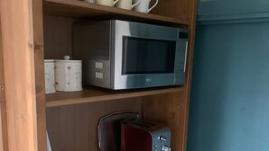 Un estante de madera con un microondas, un tostador y un menú en la repisa inferior.