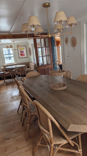 A dining area with a long wooden table, wicker chairs, and a hanging light fixture. - 7-bedroom *Seabrook Beach location *Views of Hampton Harbor (Seabrook)