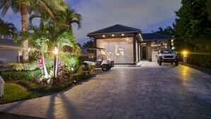 A modern house with a covered garage, a driveway, and a well-maintained garden with palm trees. - The duo of a prestigious holiday home and the comfort of a luxurious Motor Coach (Margate)