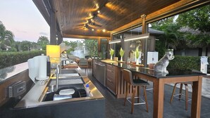 A modern kitchen with a central island, bar stools, and a dog sitting on the counter. - The duo of a prestigious holiday home and the comfort of a luxurious Motor Coach (Margate)