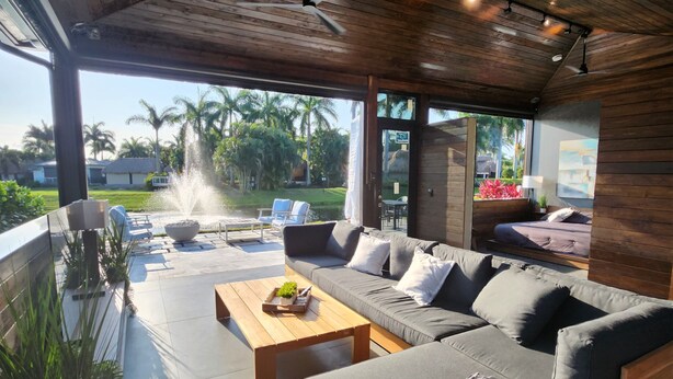 A modern outdoor living area with a wooden ceiling, a sofa set, a coffee table, and a view of a garden with a water feature. - The duo of a prestigious holiday home and the comfort of a luxurious Motor Coach (Margate)