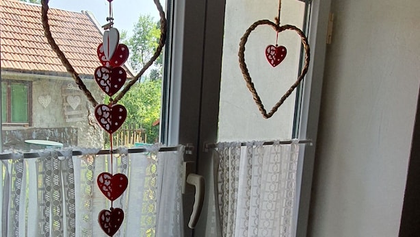 A room with a window featuring decorative heart-shaped ornaments and patterned curtains. - Viva Ve (Brinje)