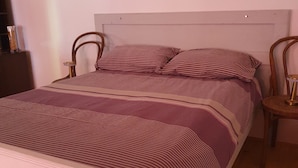 A bed with striped bedding, a wooden headboard, and two bedside tables with lamps. - Viva Ve (Brinje)