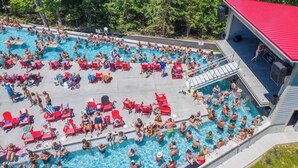 A swimming pool surrounded by red lounge chairs and a covered area with a red roof.