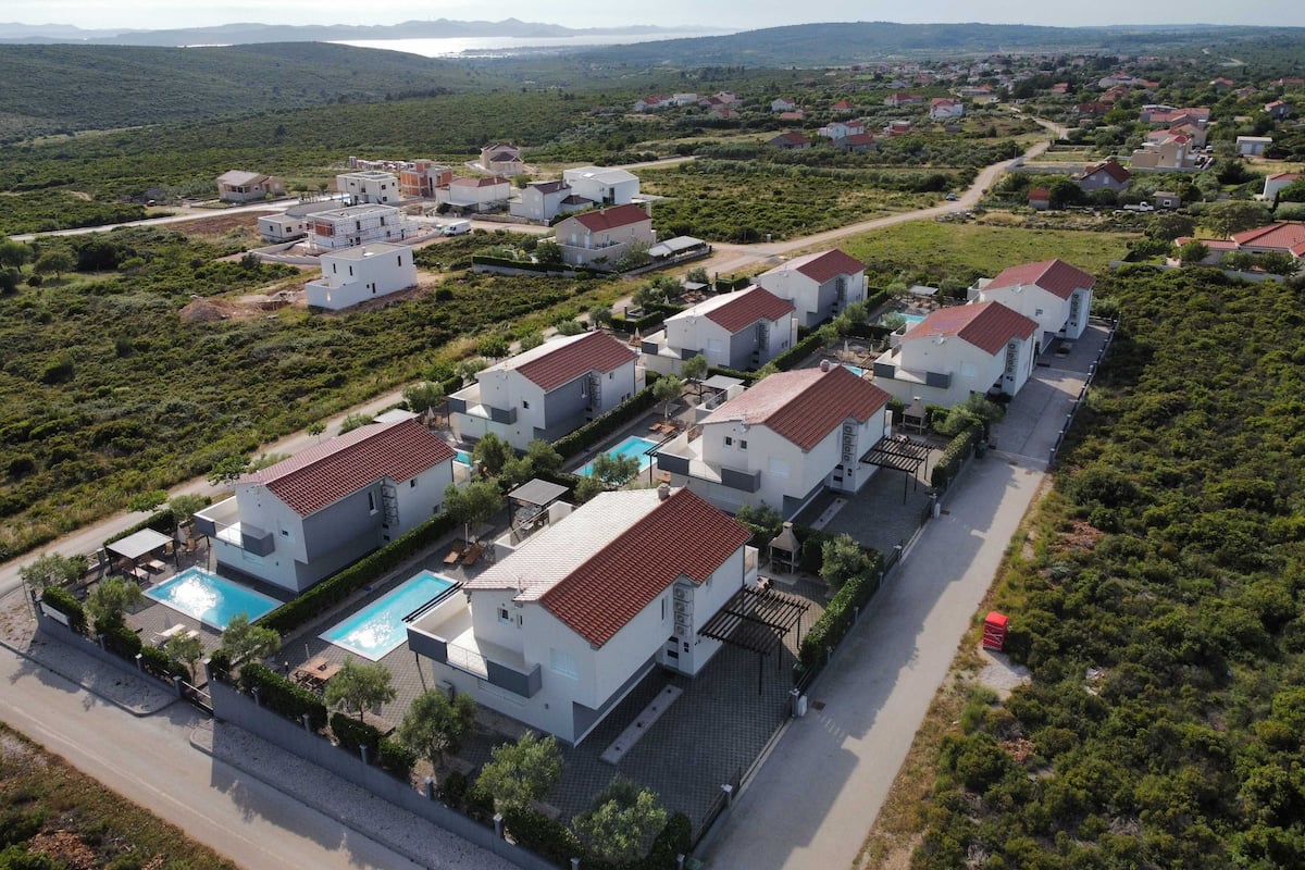 A residential area with modern houses, a swimming pool, and a road.