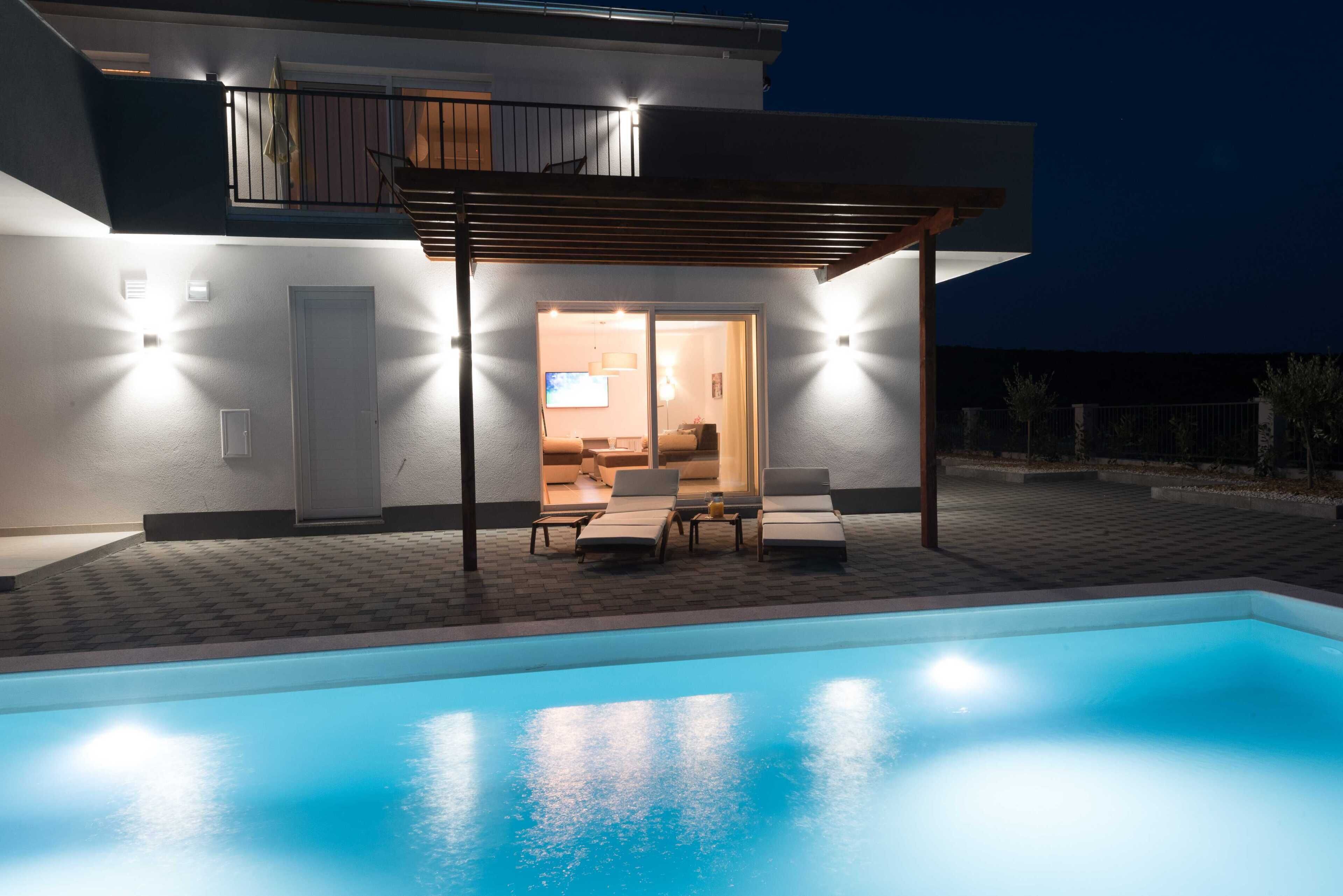 Une maison moderne dotée d’une piscine, d’un patio couvert et d’un intérieur bien éclairé.