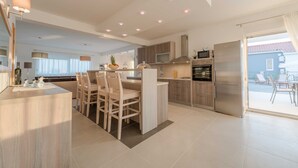 A modern kitchen with a central island, wooden cabinets, and stainless steel appliances. - Luxury Escape With Swimming Pool & Modern Design (Sukosan)
