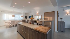 A modern kitchen with a central island, wooden cabinets, and pendant lighting. - Luxury Escape With Swimming Pool & Modern Design (Sukosan)