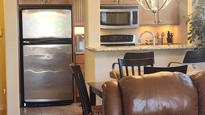 A modern kitchen with stainless steel appliances, a dining area with leather chairs, and a chandelier. - Charming 2-bedroom condo with WiFi, AC in lovely Fountain Hills (Fountain Hills)