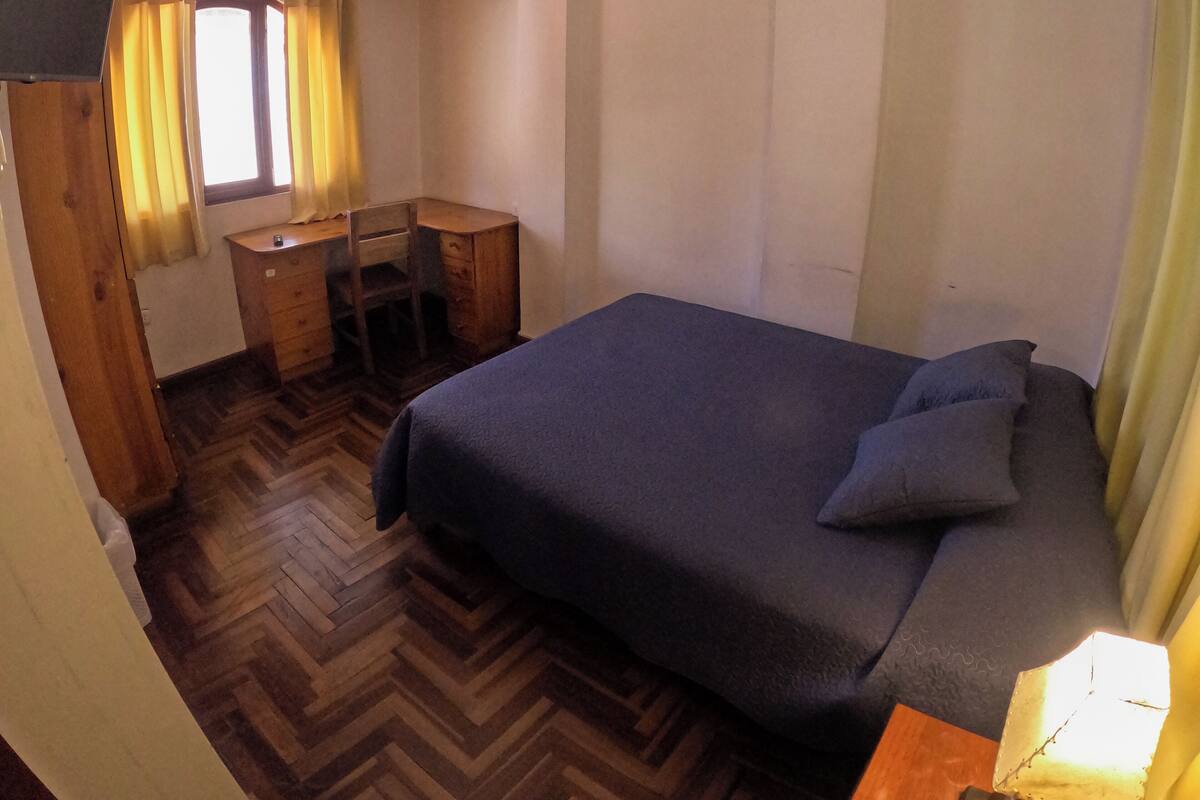 A compact room with a bed, a desk, and a chair.