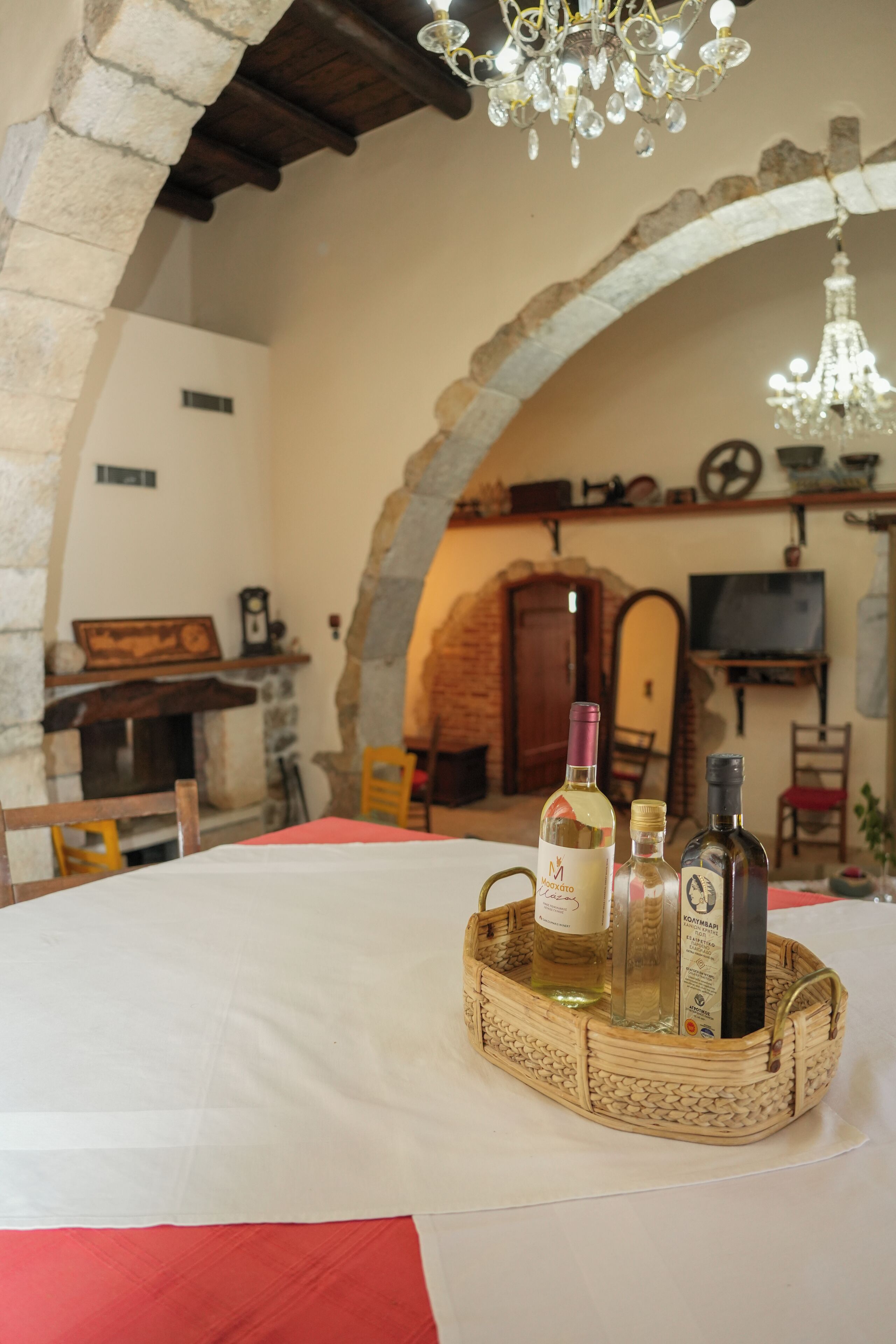 Un tavolo da pranzo con un cesto di bottiglie di vino, un lampadario, archi in pietra e decorazioni rustiche.