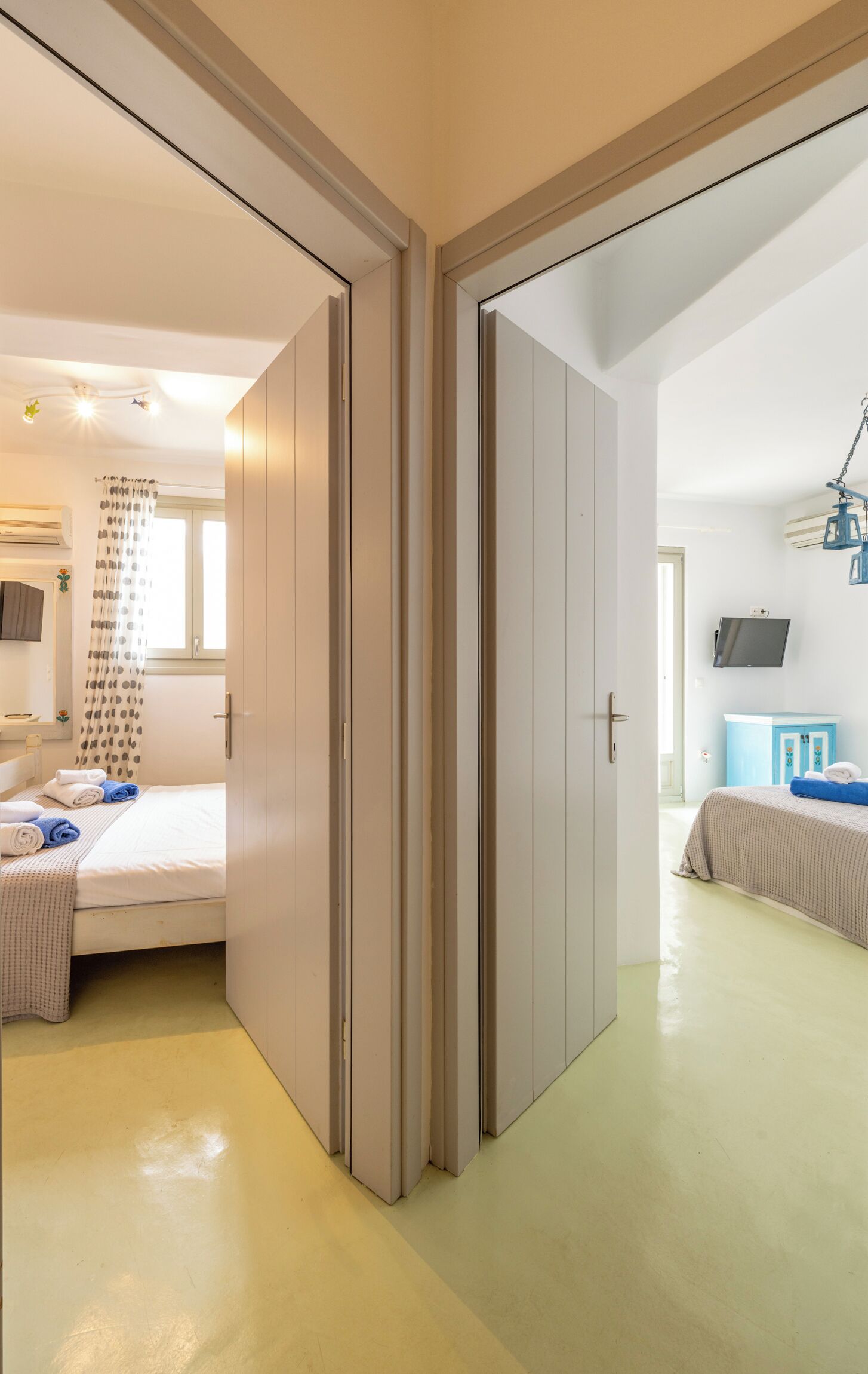 A modern bedroom with a bed, a bathroom with a shower curtain, and a TV mounted on the wall.