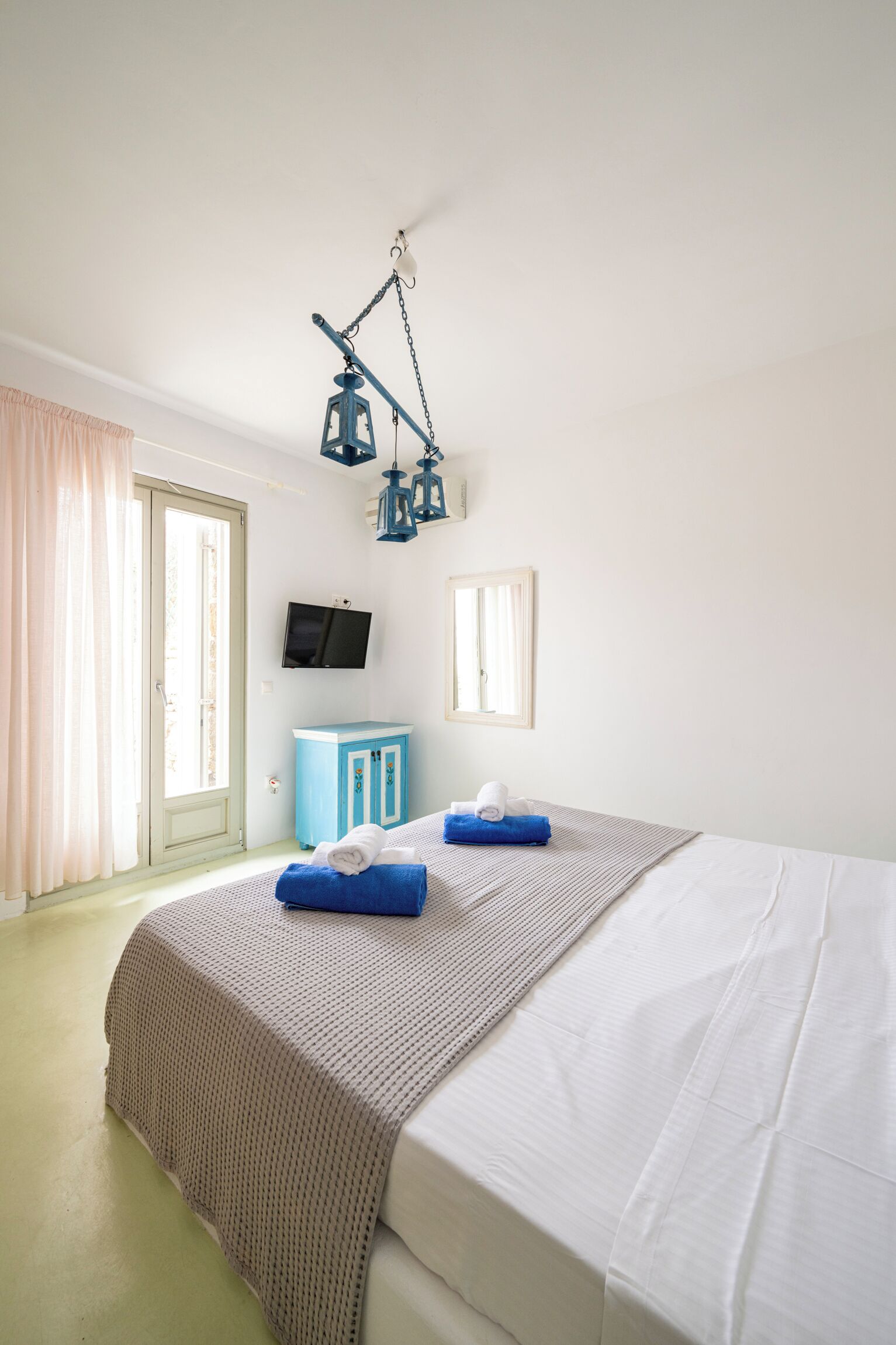Une chambre d’hôtel avec un lit, une télévision, une armoire et une fenêtre.