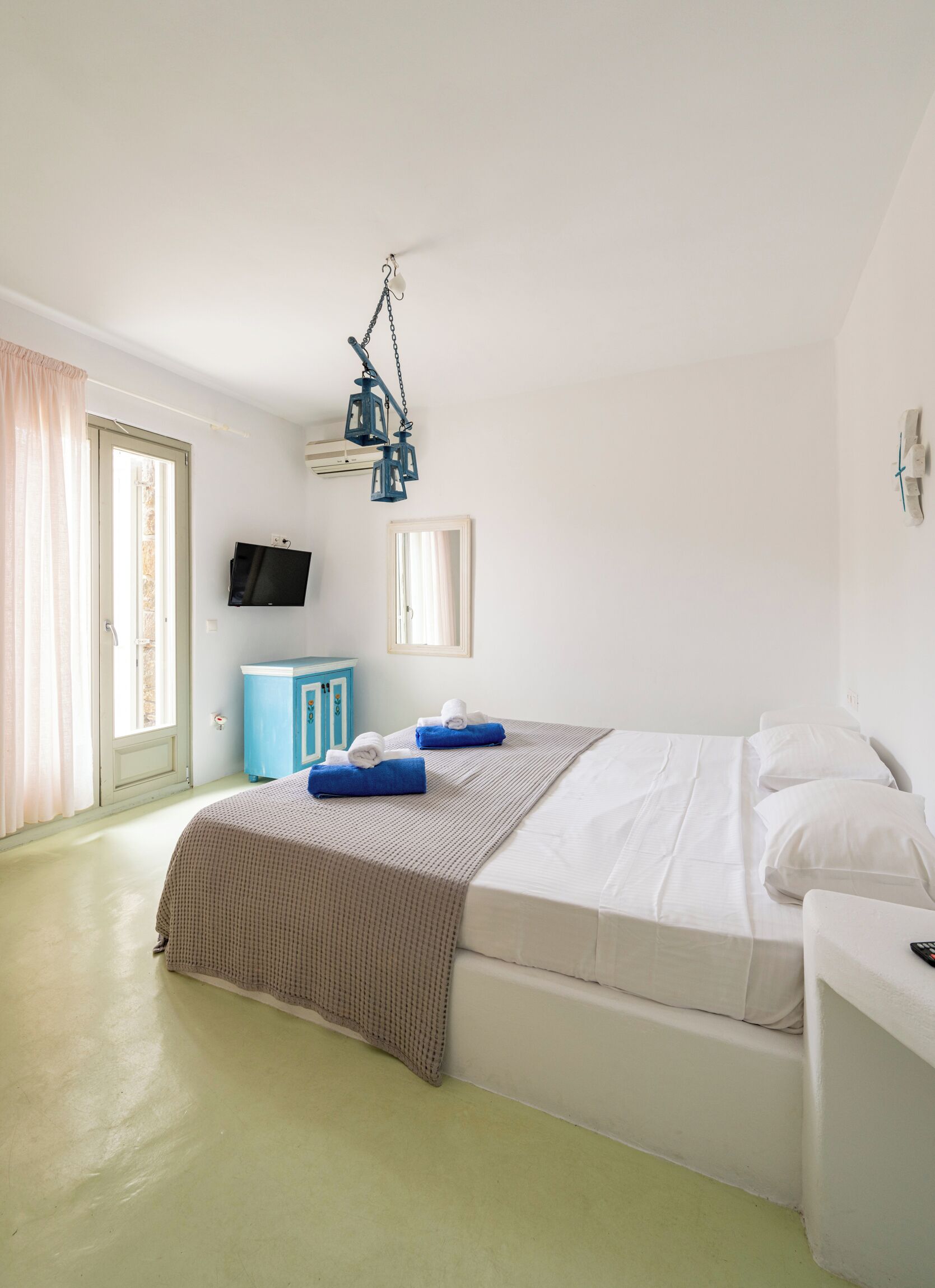 A bedroom with a bed, a TV, a wardrobe, and a window with curtains.